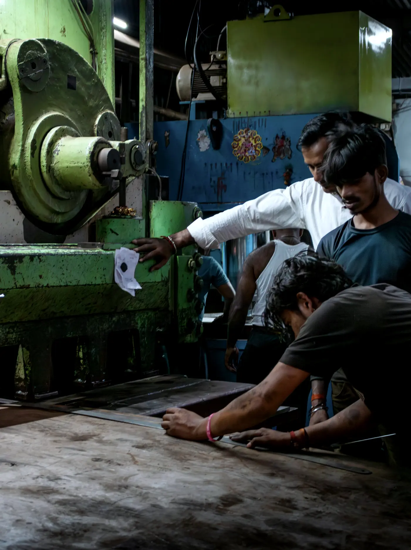 Machinists in an Indian workshop marking out a steel plate before cutting