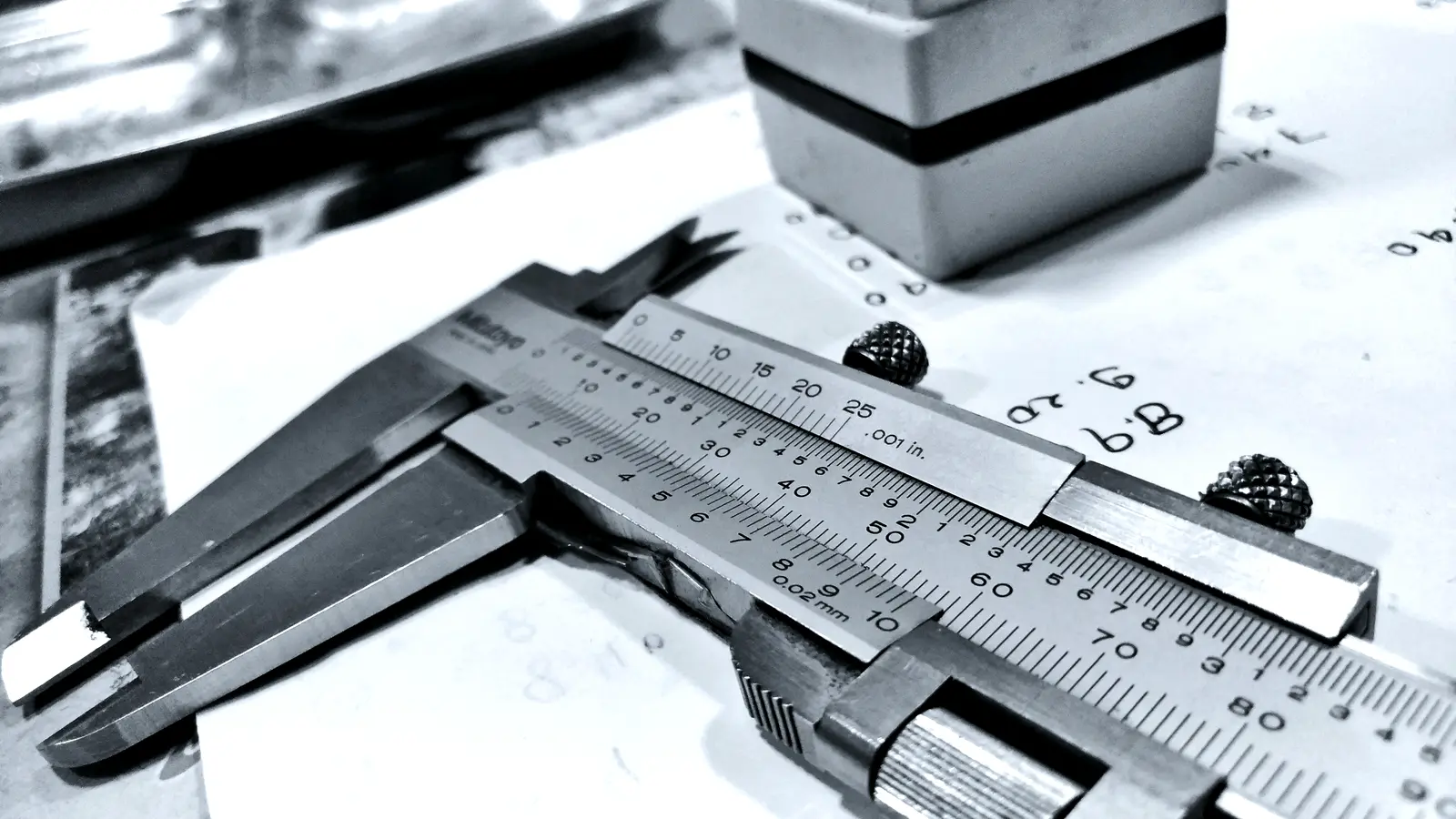 Vernier caliper measuring a machined part on a drawing