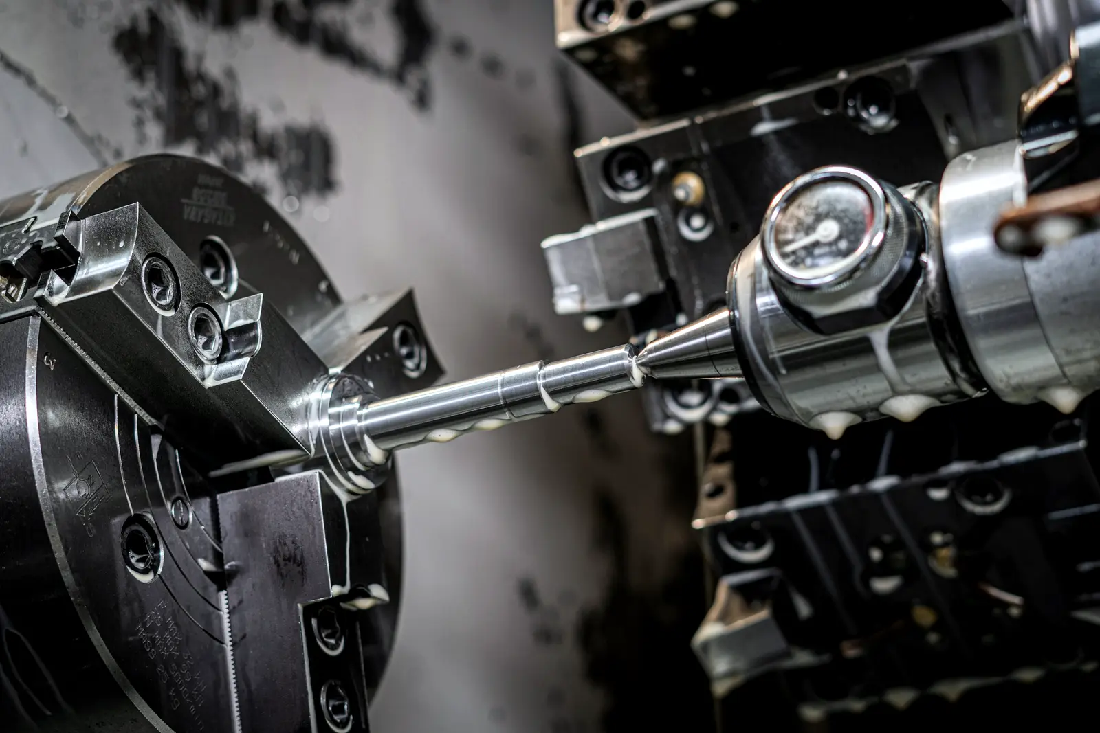 Shaft being turned on a CNC lathe, held in a chuck
